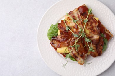 Photo of Tasty sandwich with bacon and microgreens on light grey table, top view. Space for text