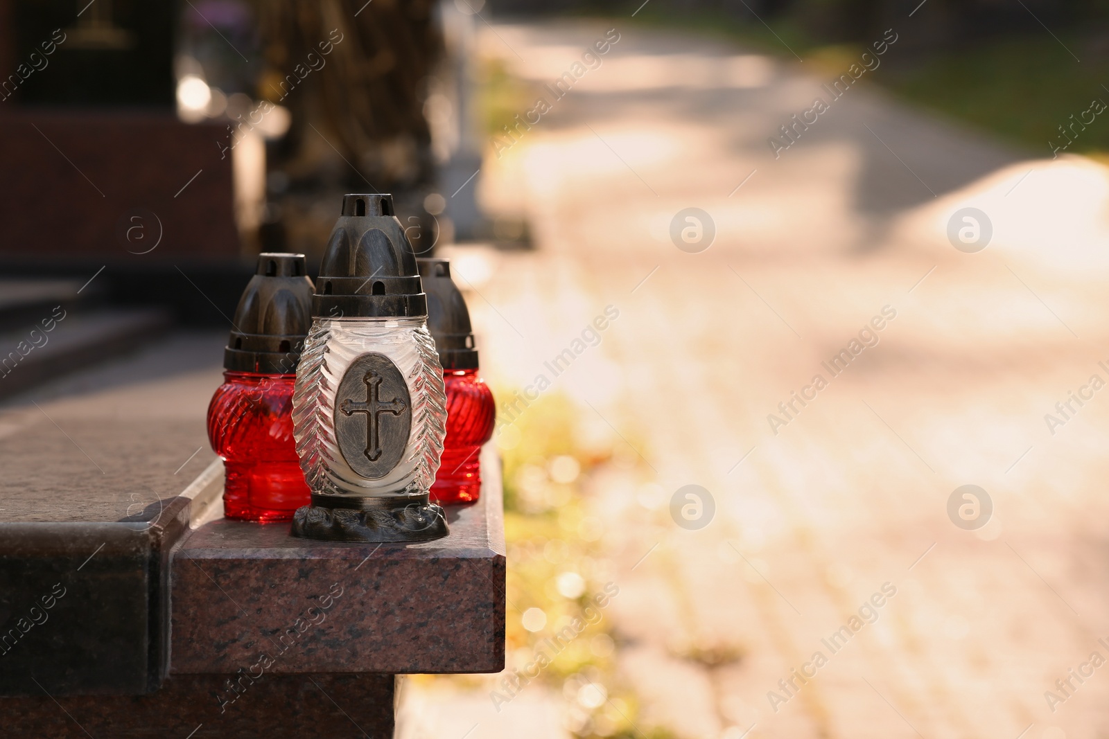 Photo of Grave lanterns on granite surface in cemetery, space for text