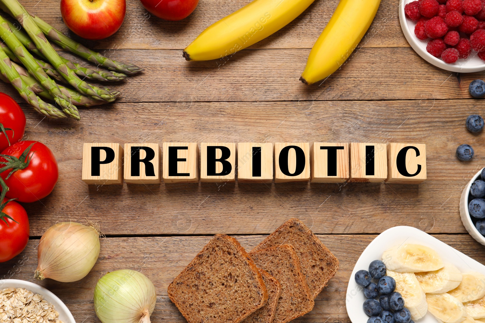 Photo of Cubes with word Prebiotic and different products on wooden table, flat lay