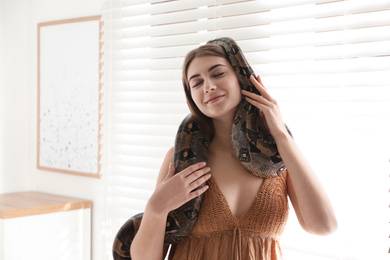 Photo of Young woman with boa constrictor at home. Exotic pet