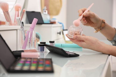 Photo of Woman applying makeup at dressing table, closeup