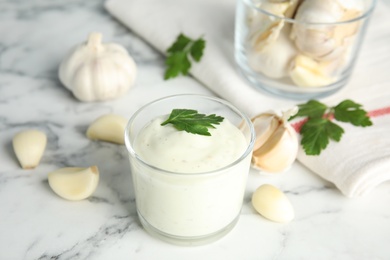 Photo of Composition with glass of garlic sauce on marble table