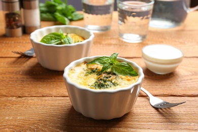 Photo of Tasty broccoli casserole in ramekins on wooden table