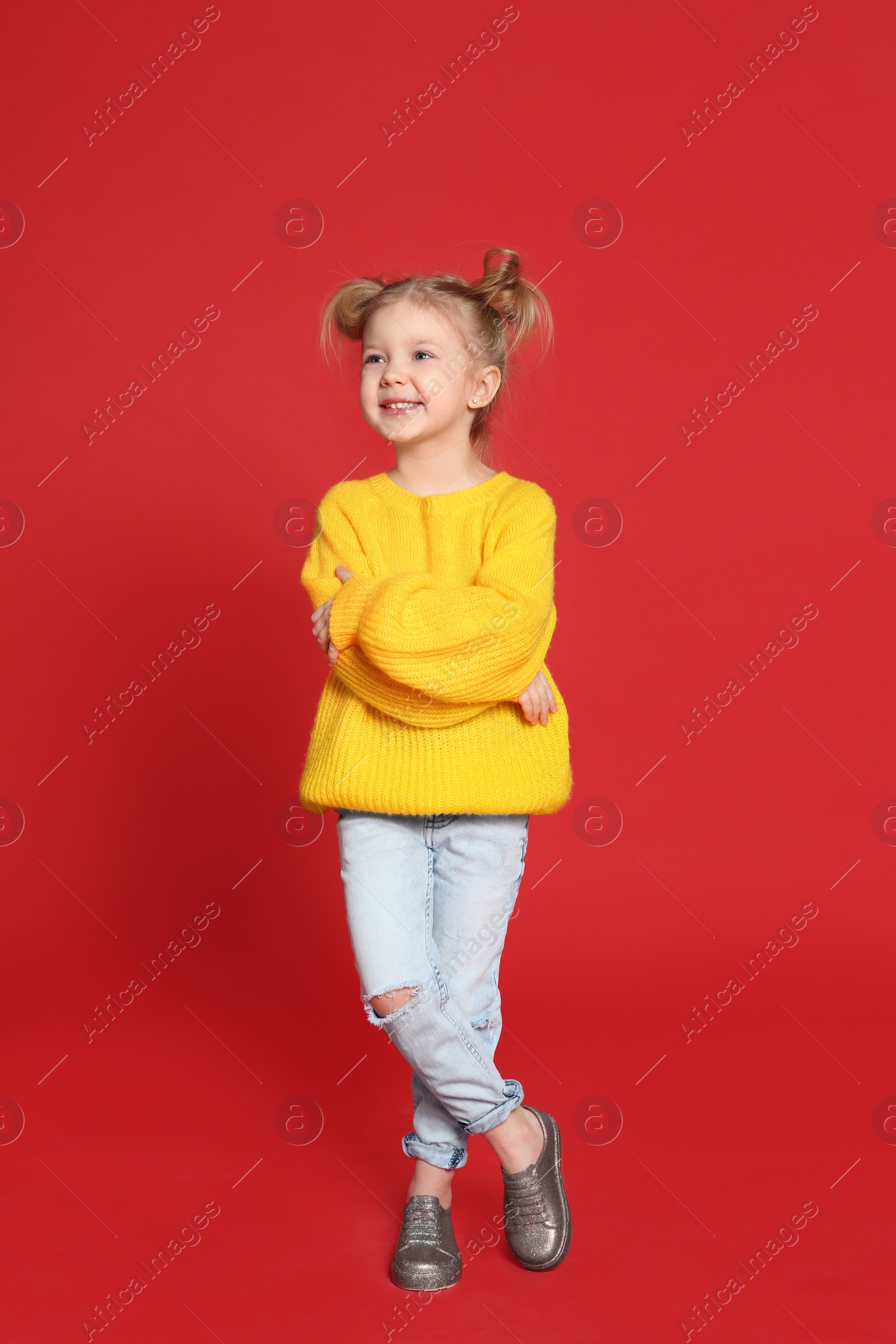 Photo of Cute little girl posing on red background