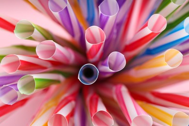 Photo of Heap of colorful plastic straws for drinks as background, closeup