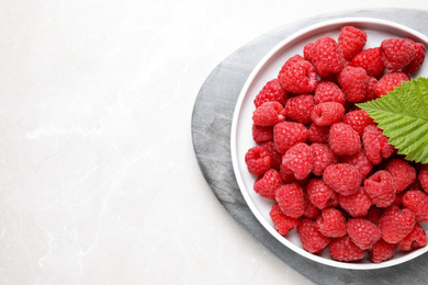 Photo of Delicious fresh ripe raspberries on light table, top view. Space for text