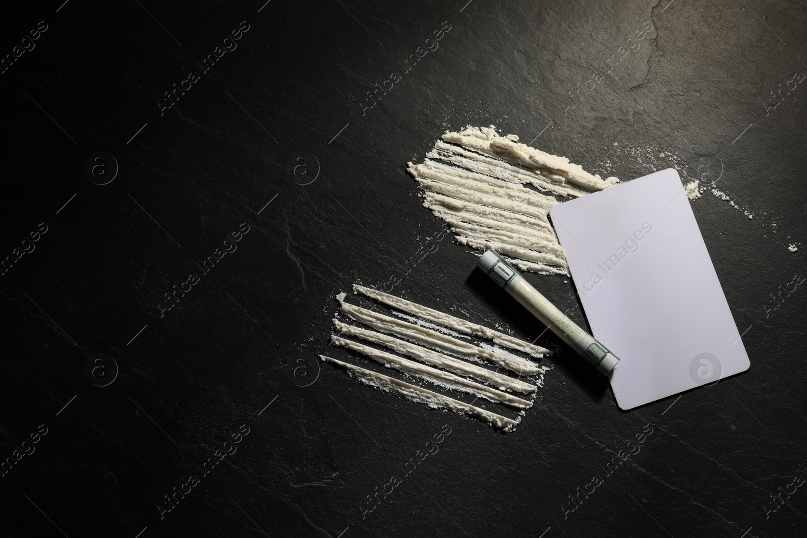 Photo of Hard drug, rolled dollar banknote and blank card on dark textured background, flat lay. Space for text