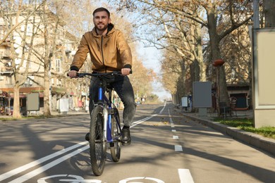 Happy handsome man riding bicycle on lane in city