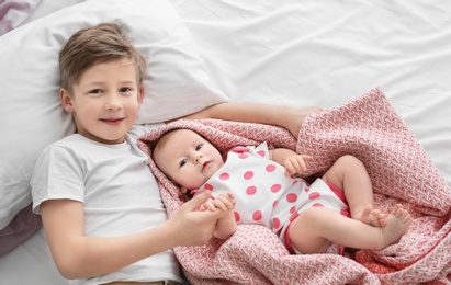 Photo of Cute little baby with elder brother lying on bed at home