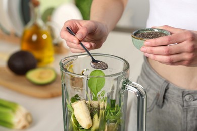 Photo of Woman adding chia seeds into blender with ingredients for green smoothie, closeup