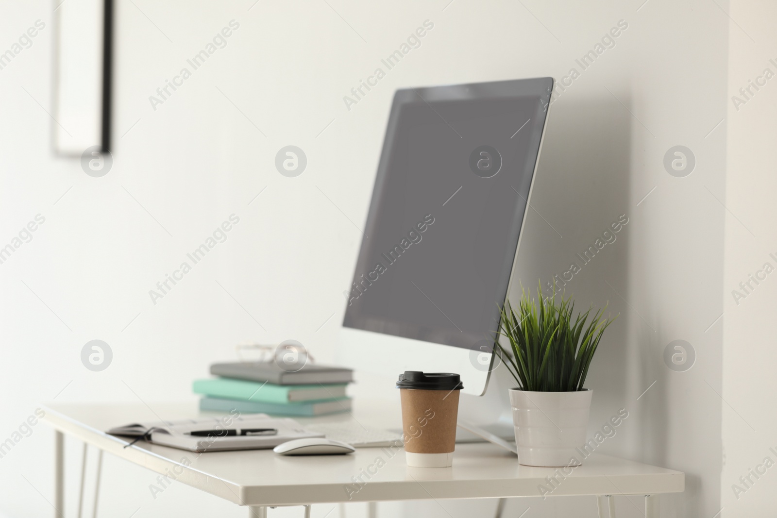 Photo of Computer, notebooks and coffee on table in office