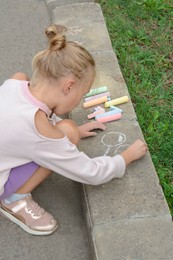 Photo of Little child drawing balloons with chalk on asphalt
