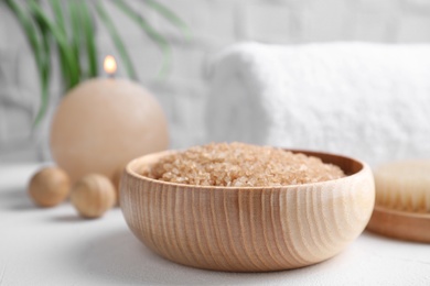 Salt for spa scrubbing procedure in wooden bowl on white table