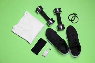 Photo of Sportswear and equipment on green background, flat lay