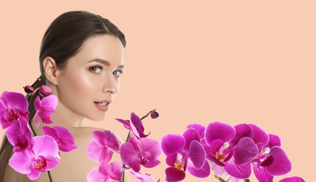 Image of Beautiful young woman and orchid flowers on light background, space for text. Spa portrait