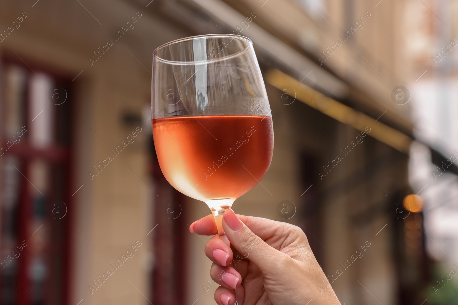 Photo of Woman holding glass of rose wine outdoors, closeup