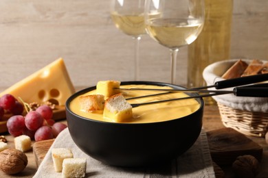 Photo of Tasty cheese fondue, snacks and wine on wooden table