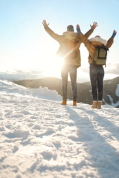 Photo of Excited couple with backpacks enjoying mountain view during winter vacation. Space for text