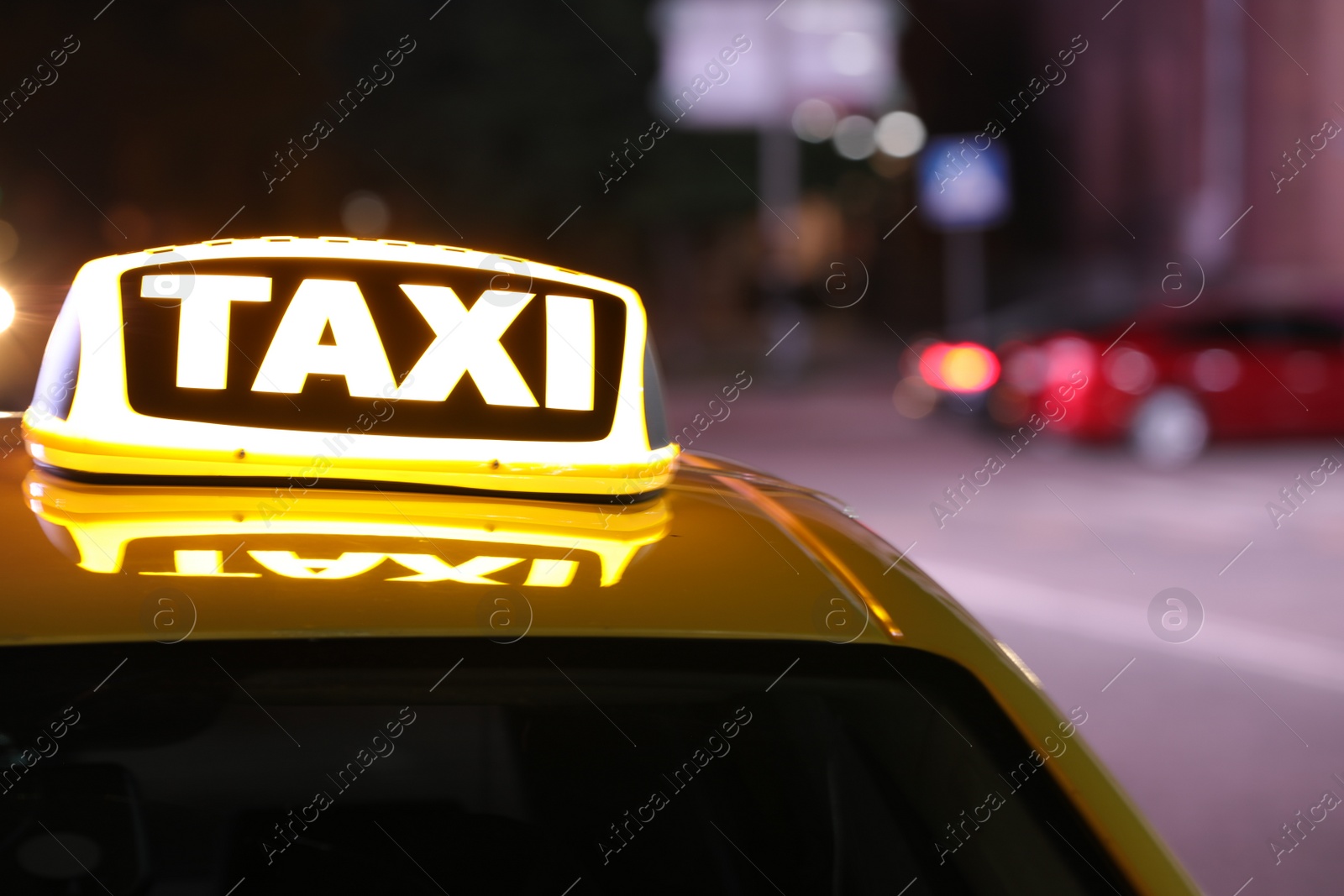 Photo of Taxi car with yellow sign on city street at night