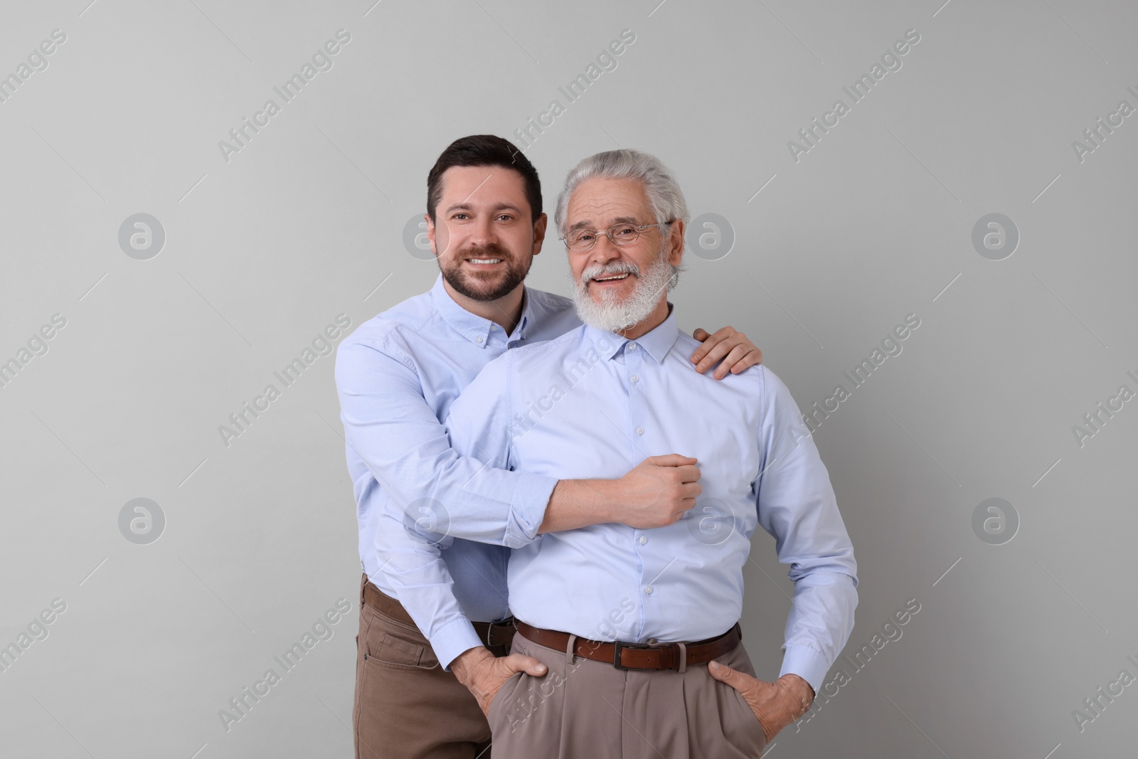 Photo of Happy son and his dad on gray background