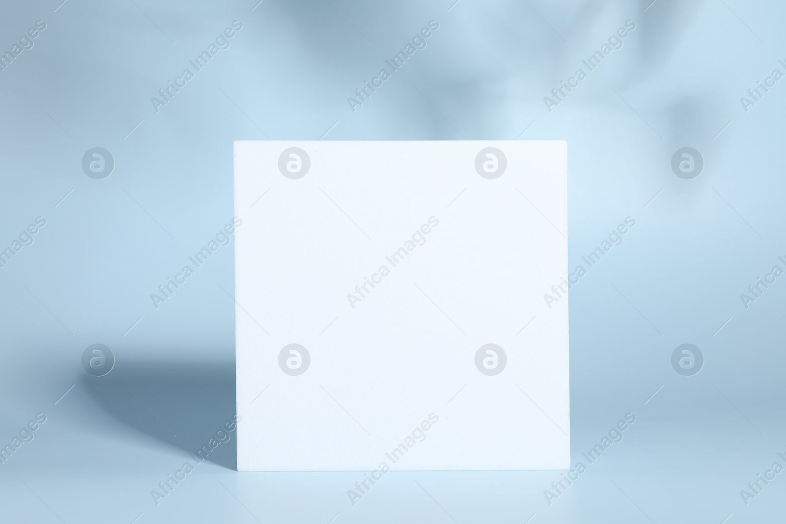 Photo of Presentation of product. White podium and shadows on light blue background. Space for text