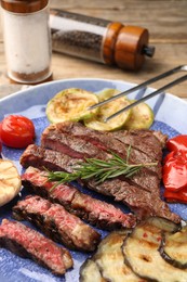 Photo of Delicious grilled beef steak with vegetables and spices on table, closeup