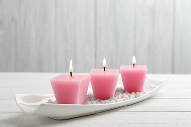 Photo of Composition with three burning candles on white wooden table