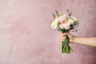 Photo of Woman holding bouquet with beautiful ranunculus flowers on color background. Space for text