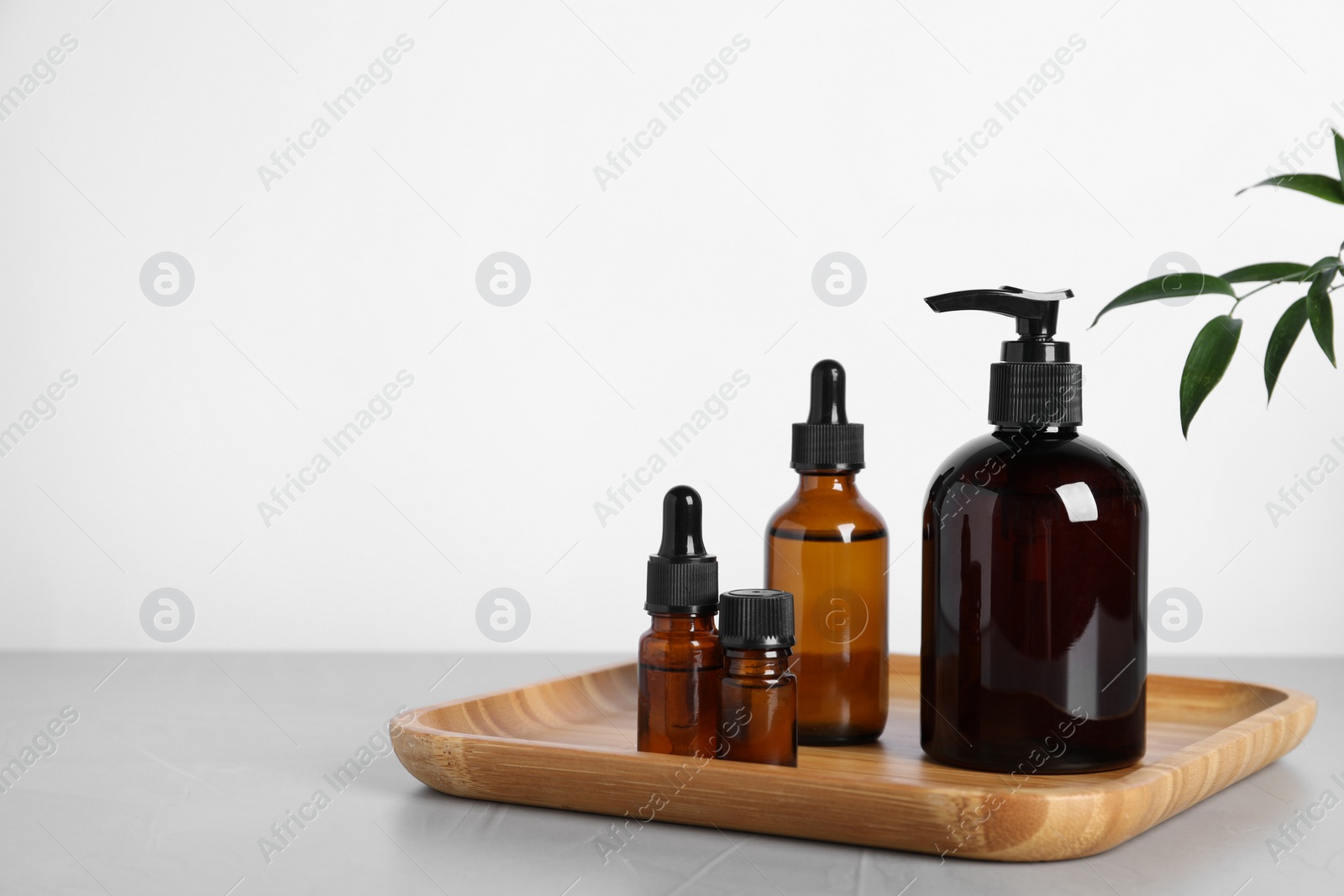 Photo of Different cosmetic products and leaves on grey table. Space for text