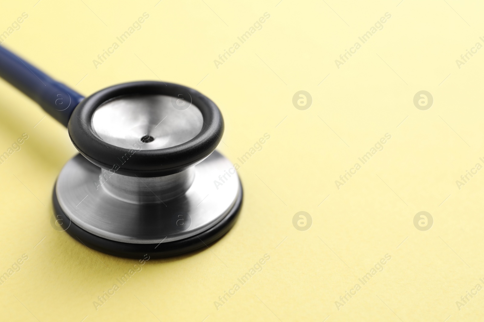 Photo of Stethoscope on yellow background, closeup. Space for text