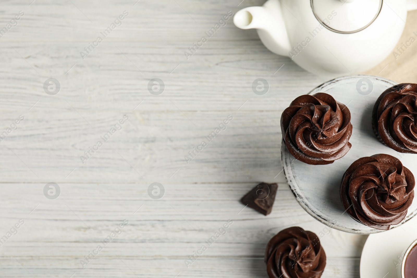 Photo of Delicious chocolate cupcakes and tea on white wooden table, flat lay. Space for text