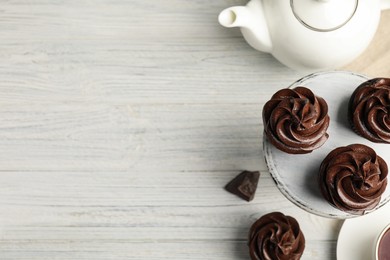 Delicious chocolate cupcakes and tea on white wooden table, flat lay. Space for text