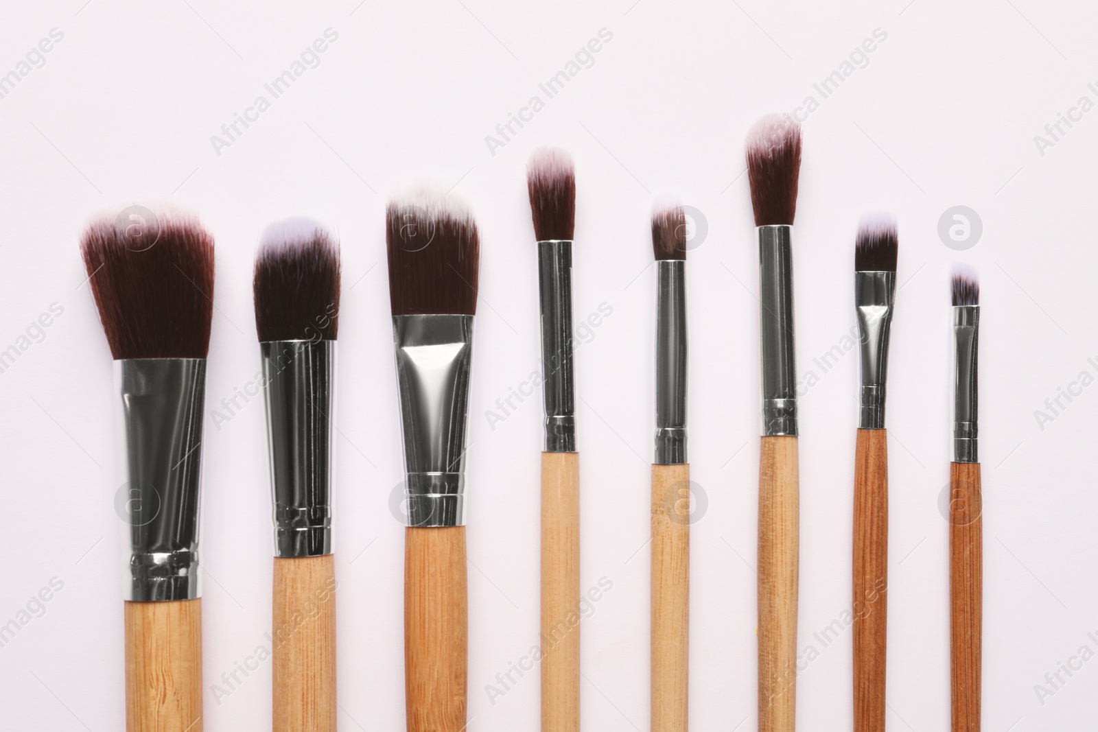 Photo of Different makeup brushes on white background, flat lay