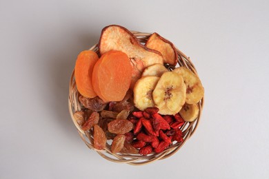 Photo of Wicker basket with different dried fruits on white background, top view