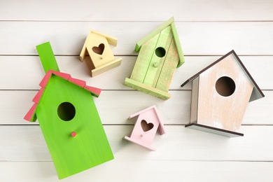 Photo of Many different bird houses on white wooden background, flat lay