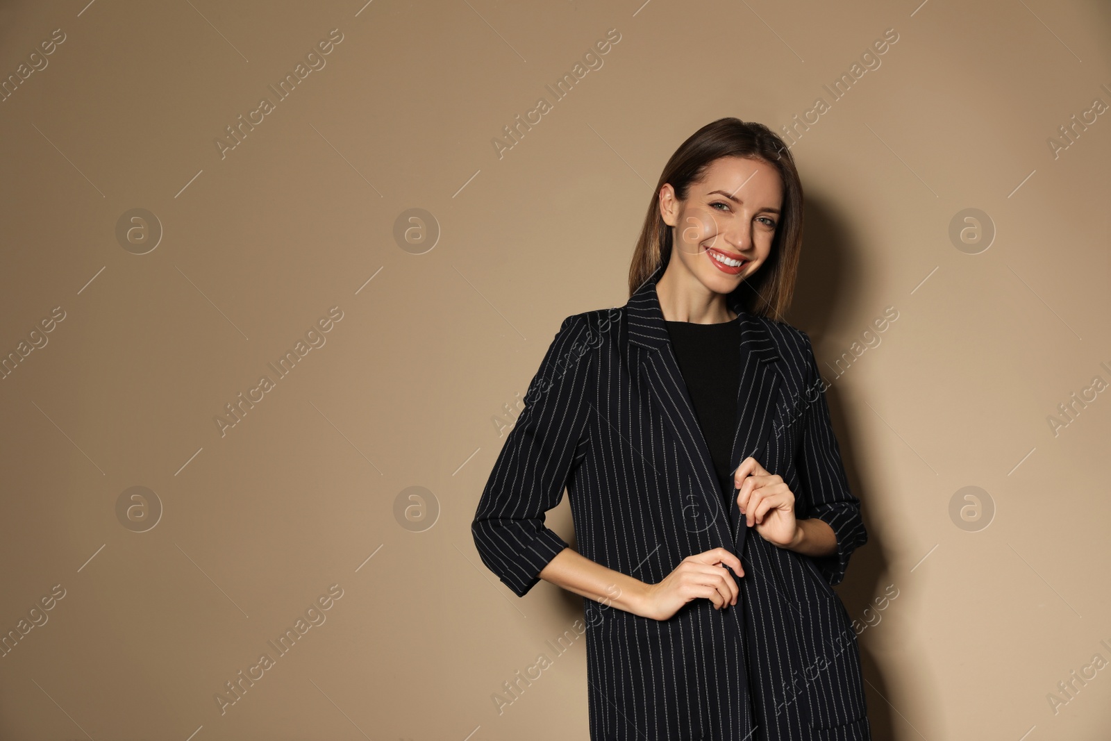 Photo of Portrait of beautiful young woman in fashionable suit on beige background, space for text. Business attire