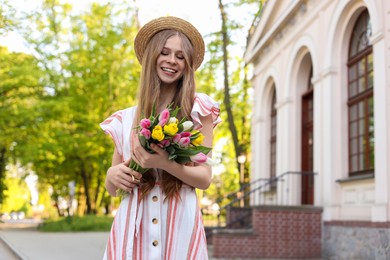 Photo of Beautiful teenage girl with bouquet of tulips on city street