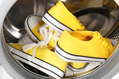 Photo of Stylish clean sneakers inside modern washing machine, closeup
