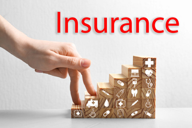 Woman, stairs made with wooden cubes and word INSURANCE on white background, closeup