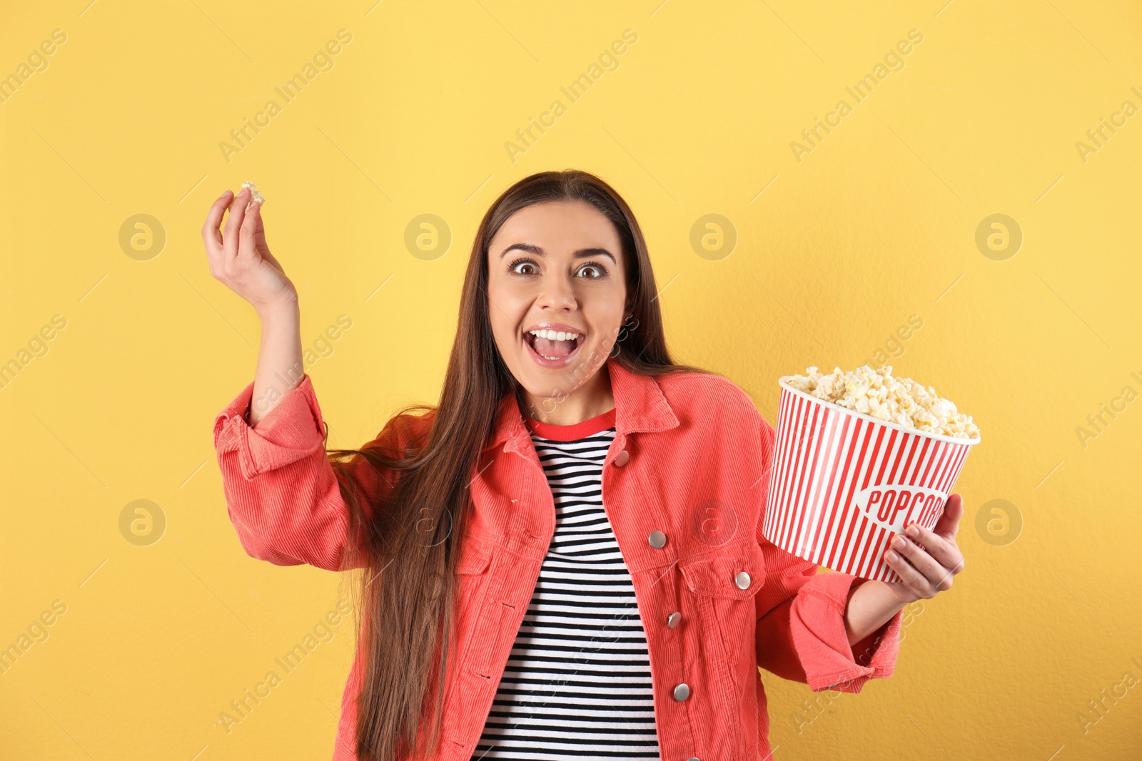 Photo of Emotional woman with tasty popcorn on color background