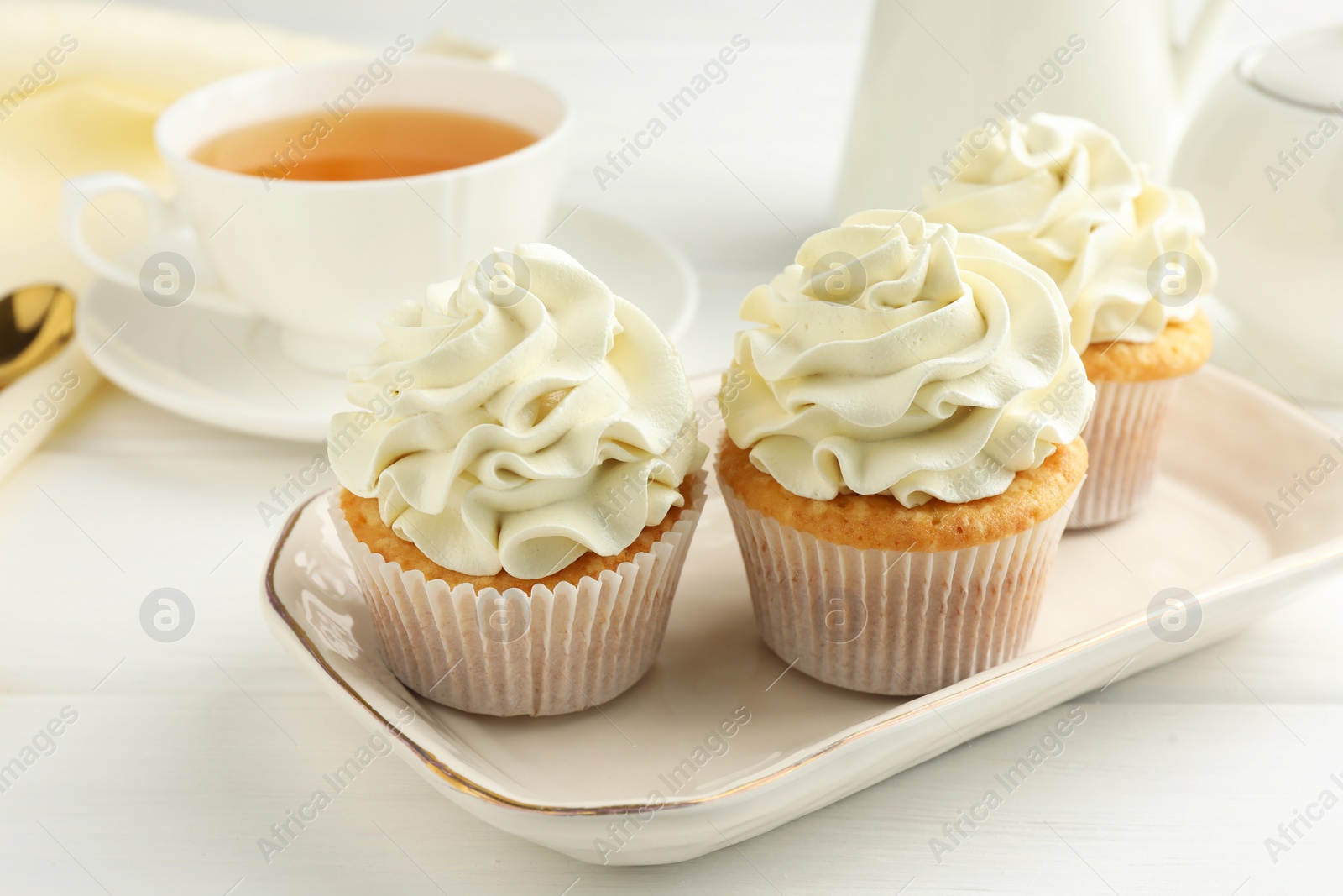 Photo of Tasty cupcakes with vanilla cream on white wooden table, closeup