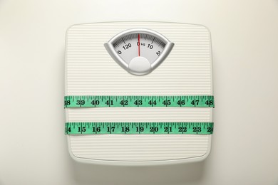 Photo of Scales tied with measuring tape on white background, top view