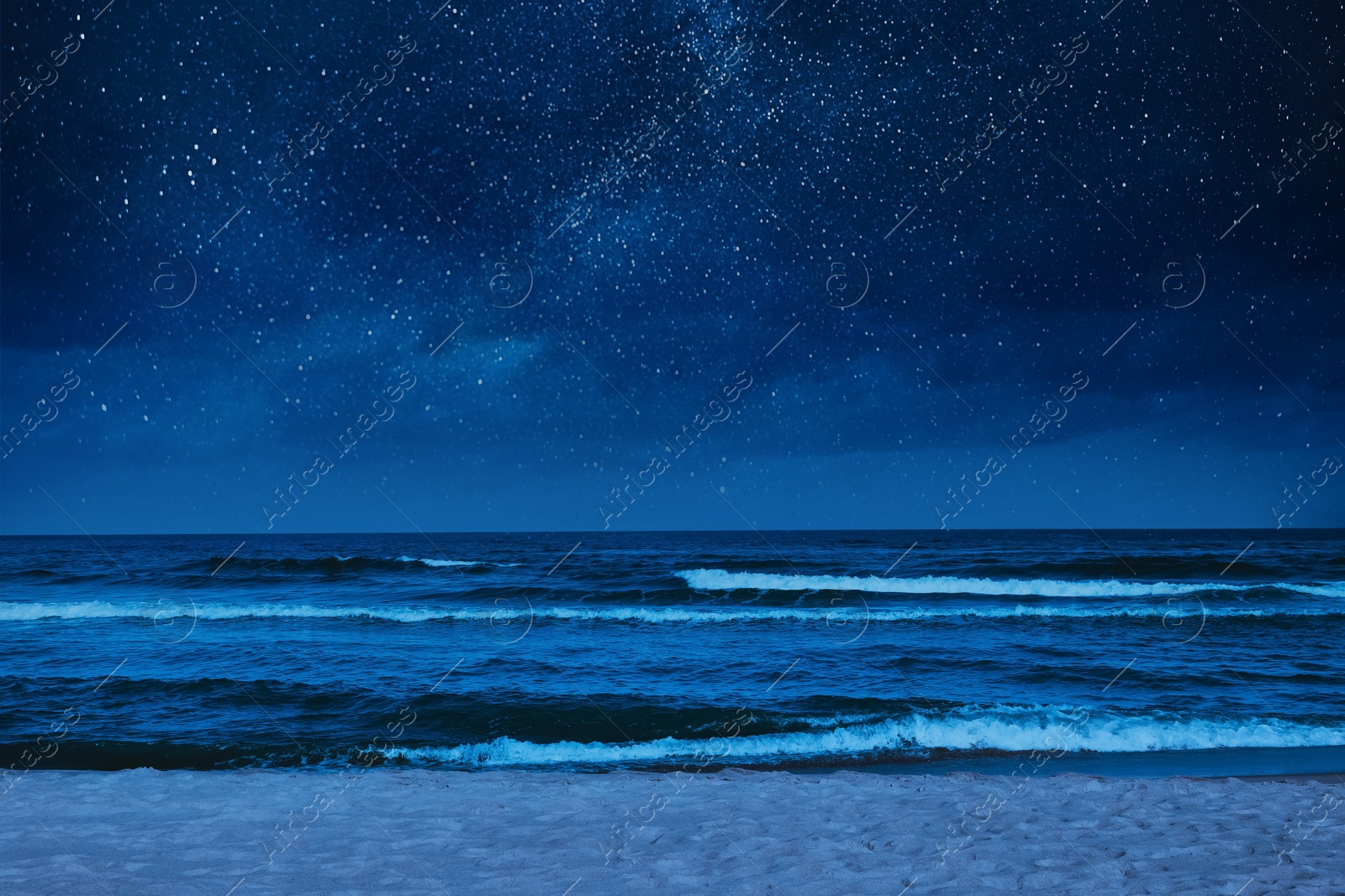 Image of Sea waves rolling onto sandy beach under starry sky at night