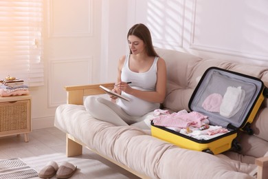 Photo of Pregnant woman packing suitcase for maternity hospital at home