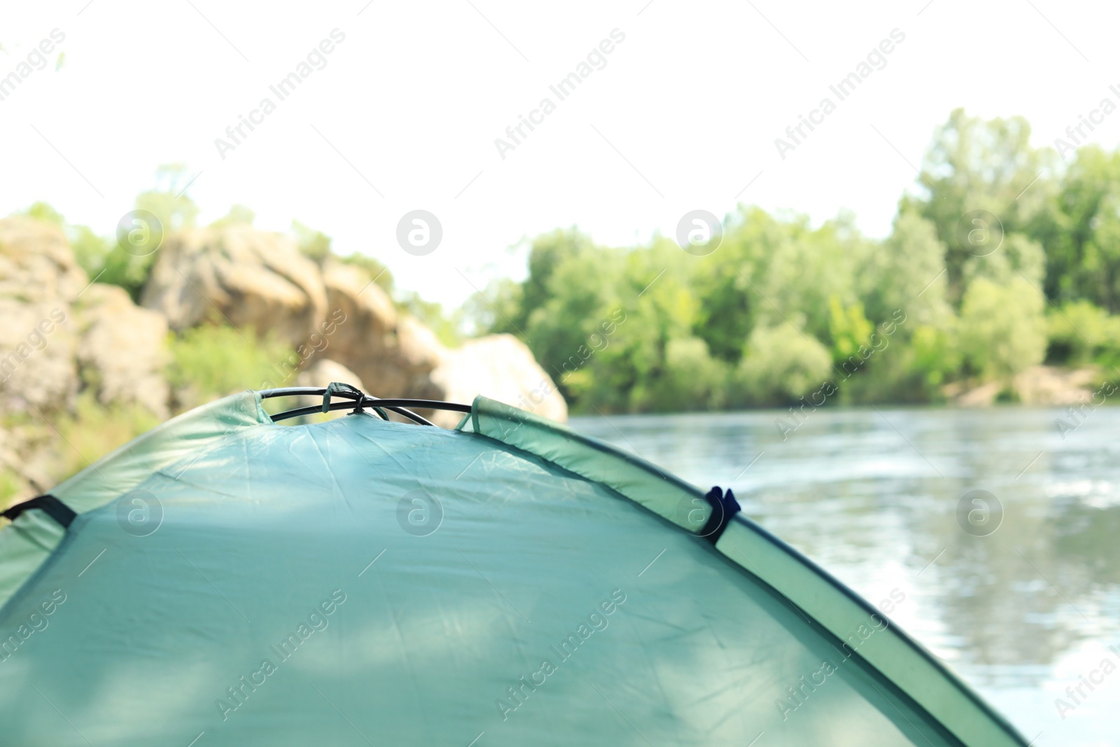 Photo of Modern camping tent on riverbank. Space for text