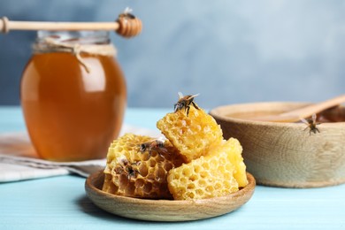 Image of Fresh delicious honeycombs and bees on light blue wooden table