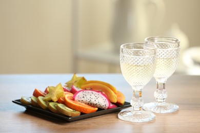 Photo of Delicious exotic fruits and wine on wooden table