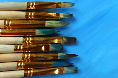 Photo of Set of different brushes on abstract colorful paint, top view