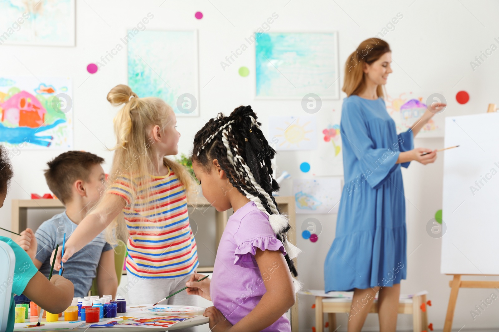 Photo of Children with female teacher at painting lesson indoors