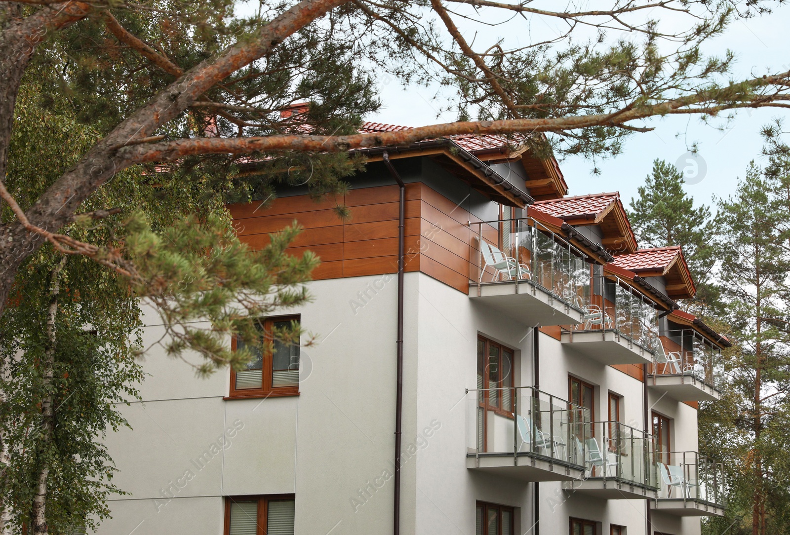 Photo of Beautiful beach house with balconies and trees outdoors